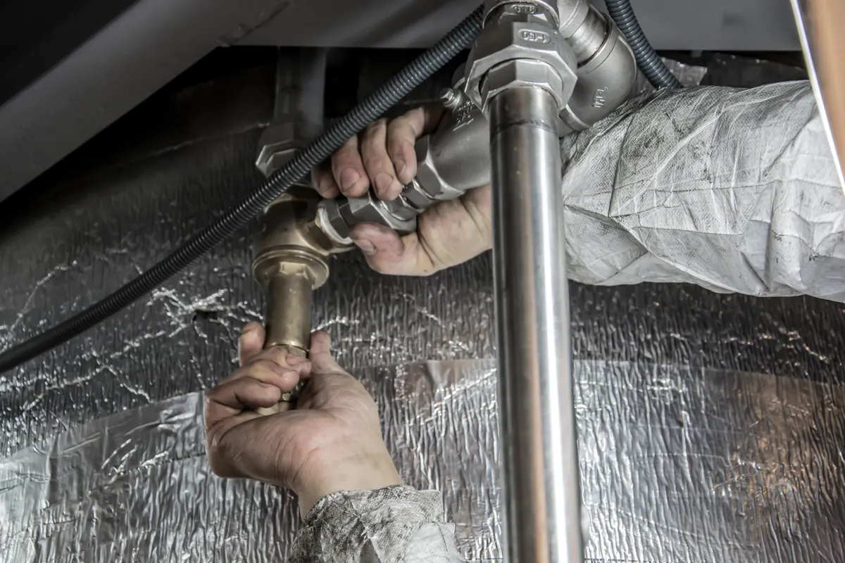 Hands tightening supply connections on copper and steel pipework